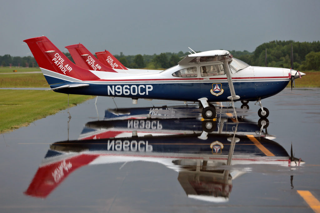 Fileira de aviões Cessna da Civil Air Patrol, alinhados em um pátio.